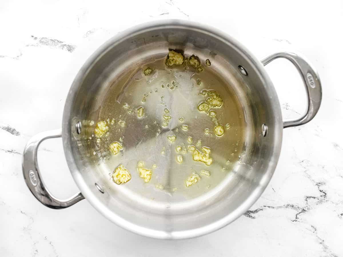 Garlic sautéing in a pot with oil