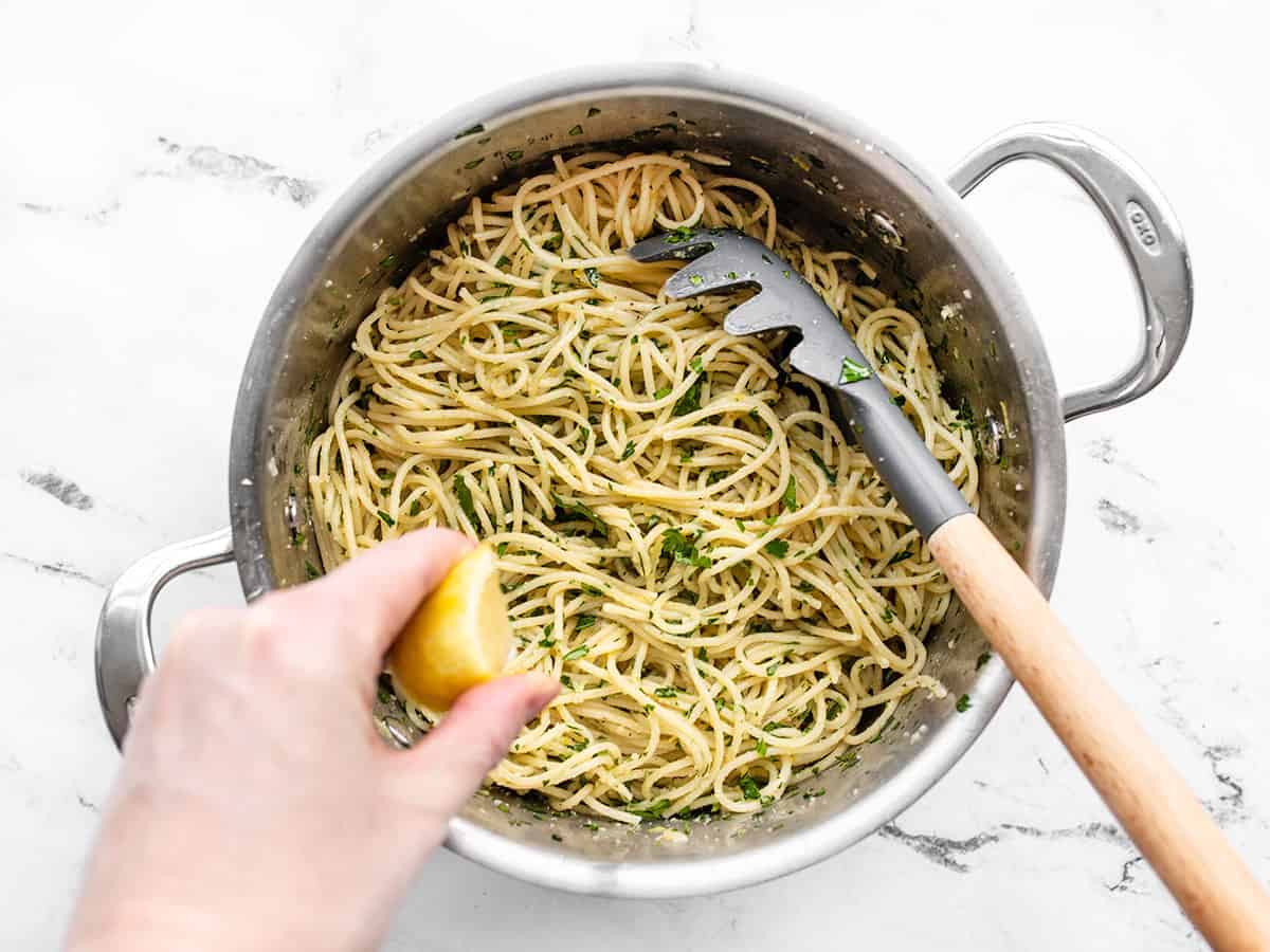 Lemon being squeezed into the pasta in the pot