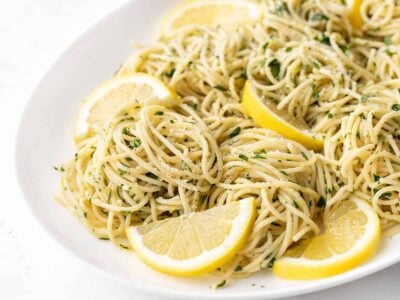 Close up side view of lemon parsley pasta on a platter with lemon slices