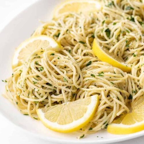 Close up side view of lemon parsley pasta on a platter with lemon slices