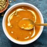 One bowl of easy tomato soup with sour cream swirled in and a gold spoon in the middle