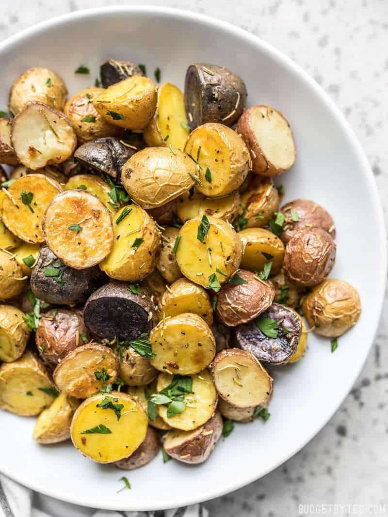 Rosemary Roasted Potatoes in a white bowl with chopped parsley sprinkled over top. 