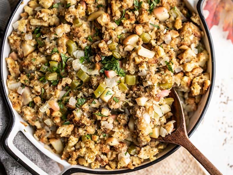 Close up overhead shot of Apple Walnut Stuffing in the casserole dish with a wooden spoon in the corner