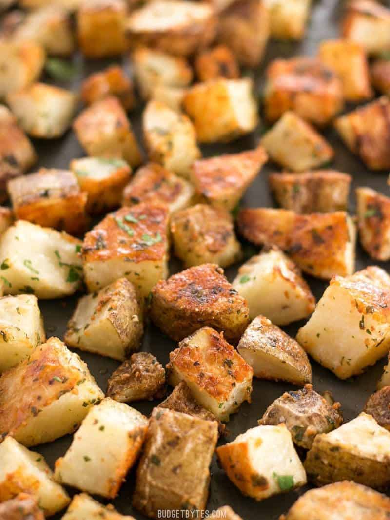 Parmesan Roasted Potatoes close up on a baking sheet, garnished with parsley