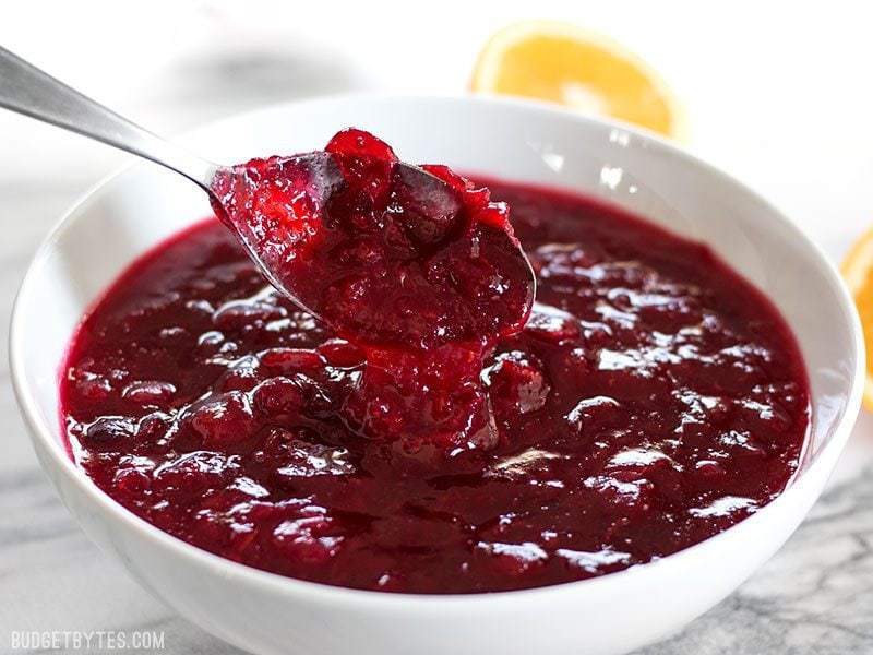 cranberry sauce dripping off a spoon into a bowl