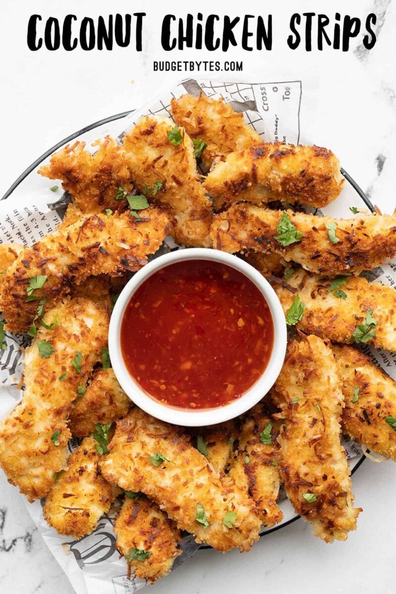 Overhead view of a plate full of coconut chicken strips with sweet chili sauce, title text at the top