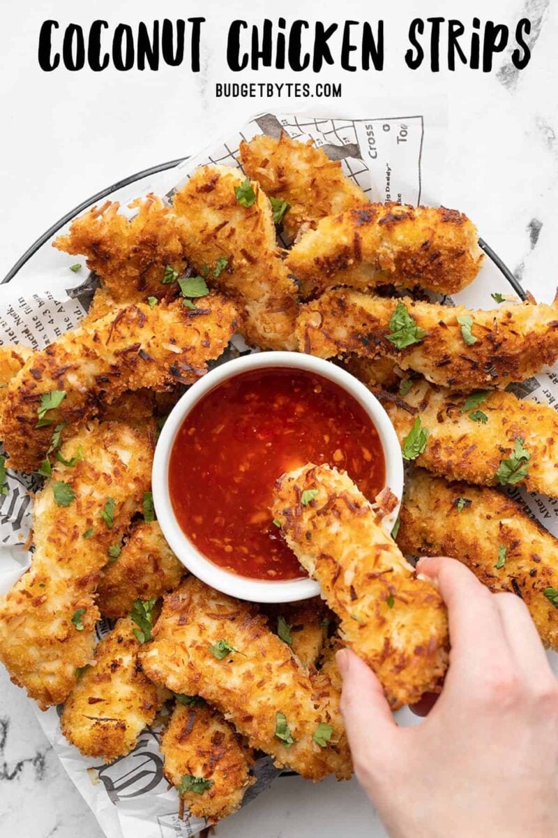 A hand dipping one coconut chicken strip into a bowl of sweet chili sauce, title text at the top