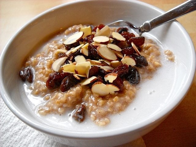 a bowl of spiced coconut steel-cut oats topped with almonds and raisins