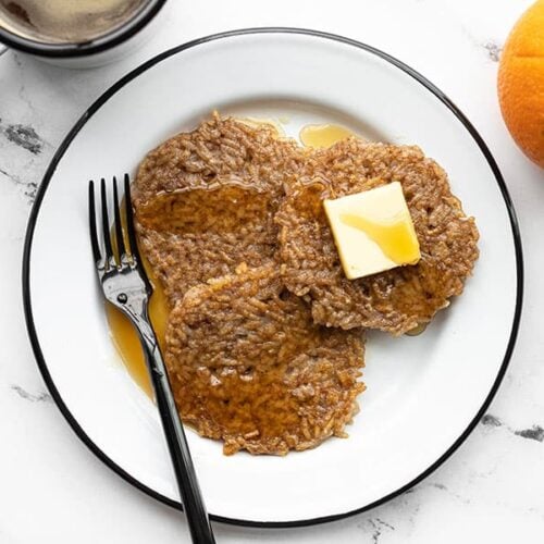 Overhead view of a plate with three rice pancakes, a cup of coffee and orange on the side