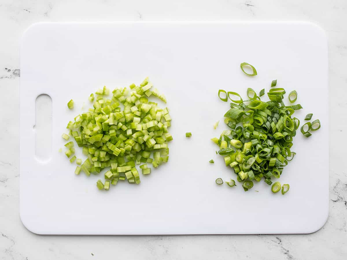 Diced celery and sliced green onion on a cutting board