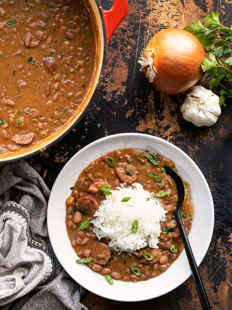 A serving of red beans and rice next to the pot full of red beans.