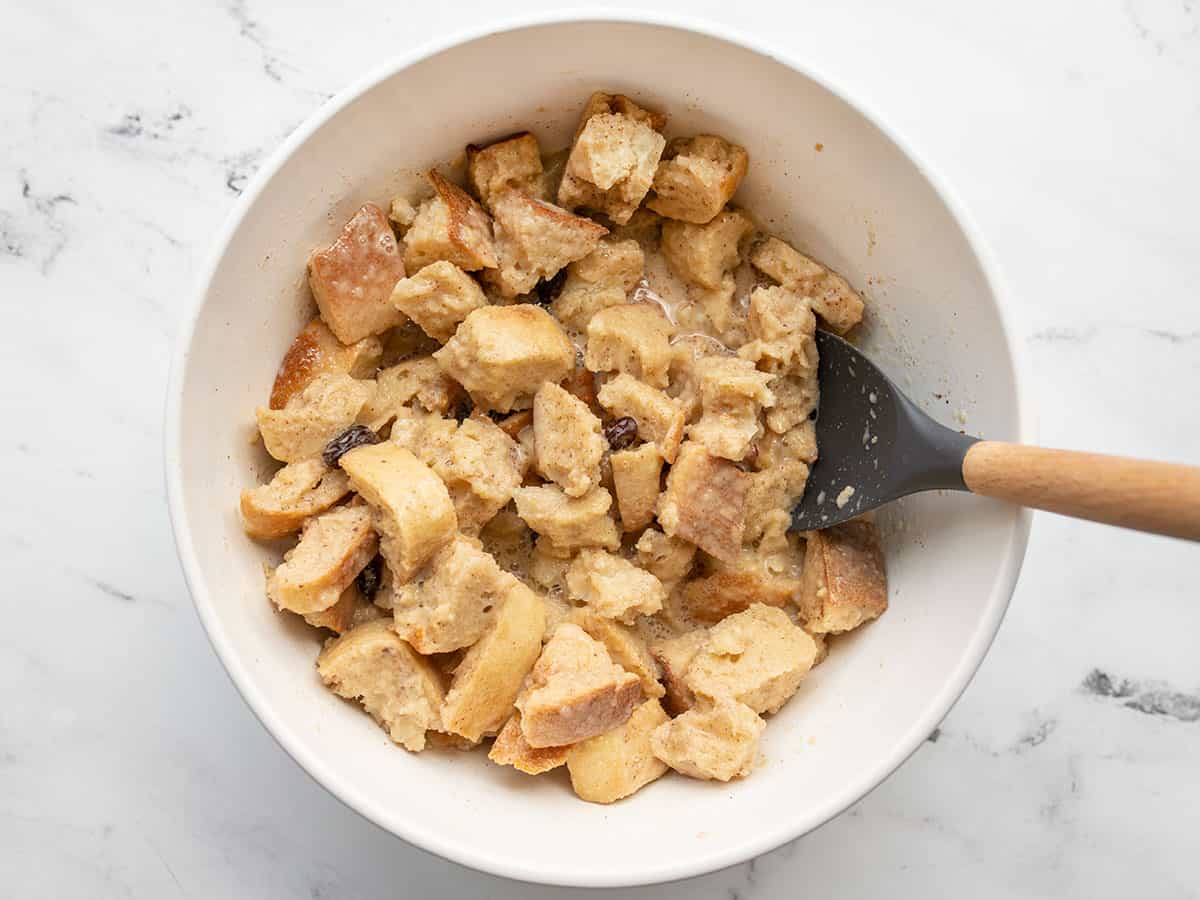 Bread soaked in custard in a bowl with a spatula