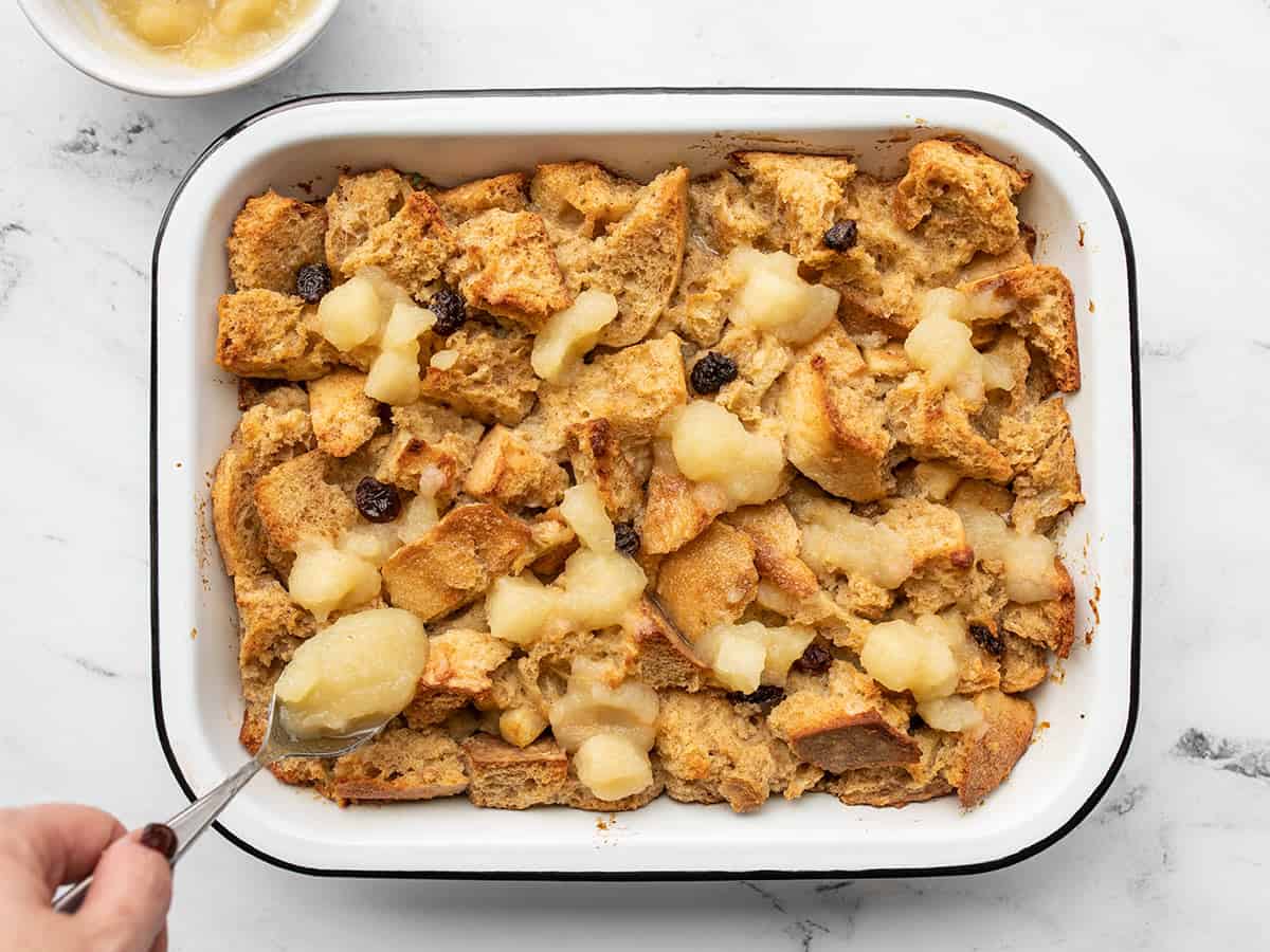 Baked bread pudding in the dish, applesauce being added on top