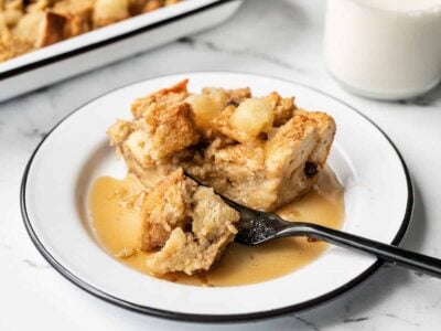 Close up of a fork cutting into a piece of apple cinnamon bread pudding