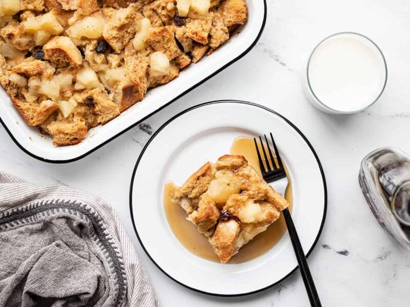 Overhead view of a piece of bread pudding on a plate next to the casserole dish