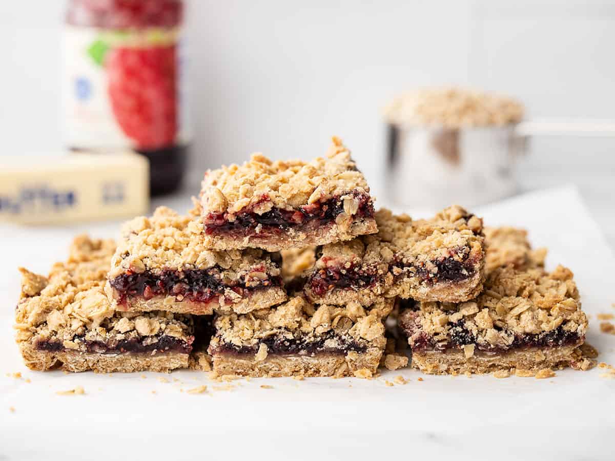 A pyramid of raspberry oatmeal bar squares with baking ingredients in the background