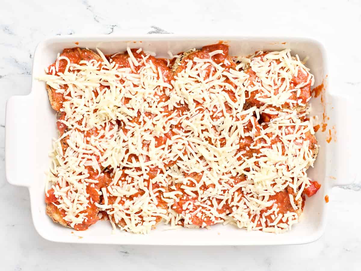 Eggplant parmesan in a baking dish topped with cheese.
