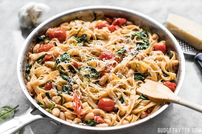 Tuscan white bean pasta in the skillet with a wooden pasta fork in the side