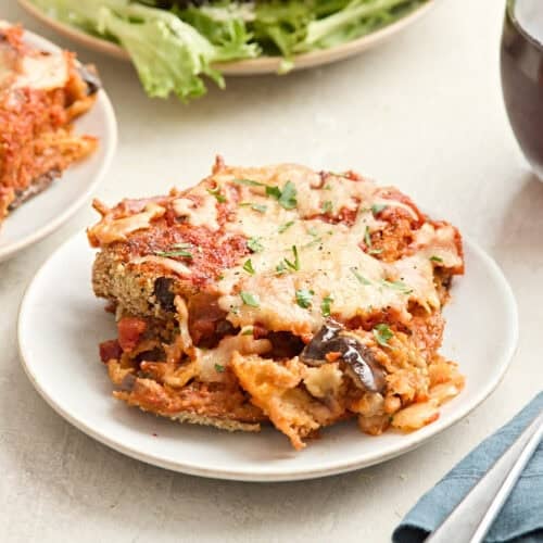 Side view of a slice of eggplant parmesan on a plate.