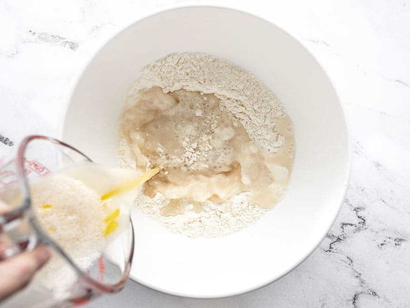 Yeast water and oil being poured into bowl with flour and salt