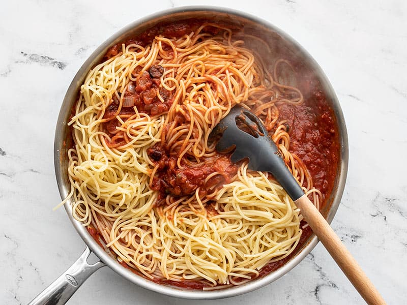 Add cooked spaghetti to puttanesca sauce in the skillet