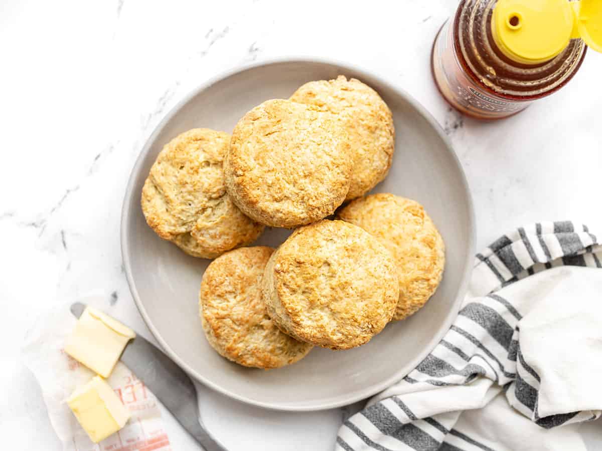 Overhead view of a plate full of butter biscuits with honey and butter on the sides