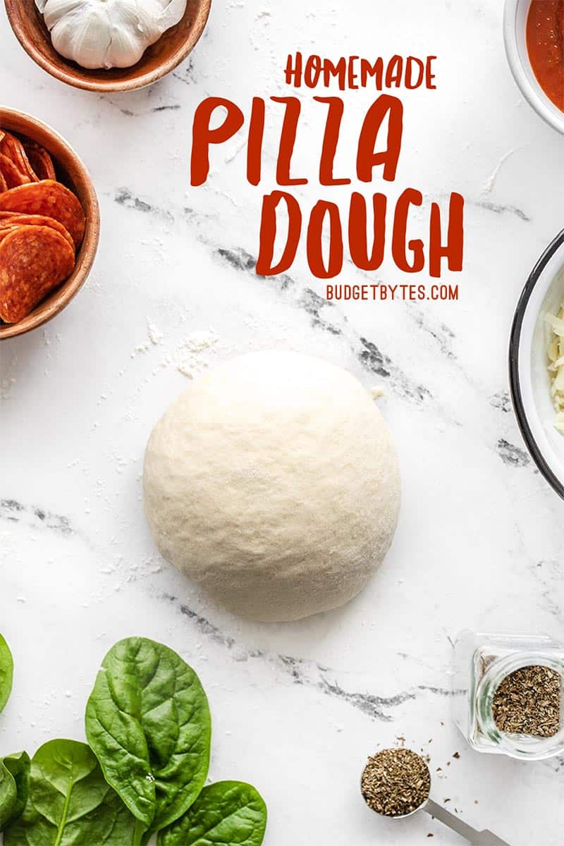 A kneaded ball of homemade pizza dough with toppings on the sides