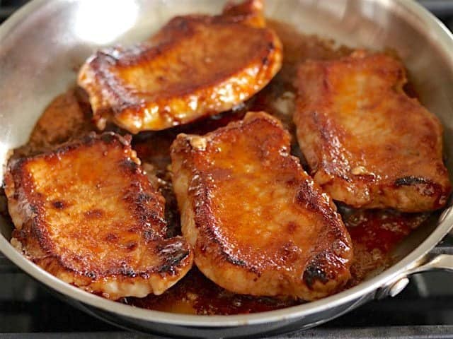 Glazed Pork Chops flipped on other side, cooking in skillet 