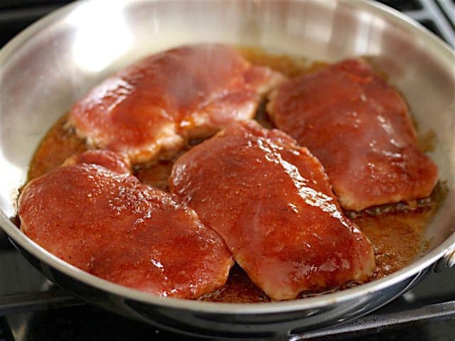 Glazed Pork Chops in skillet cooking on one side 
