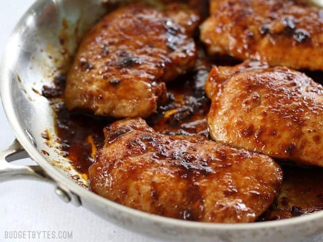 These juicy Glazed Pork Chops are sweet, salty, and a little spicy. The sugar glaze helps keep the chops moist and tender! Budgetbytes.com Close up of tender juicy Glazed Pork Chops in the skillet.
