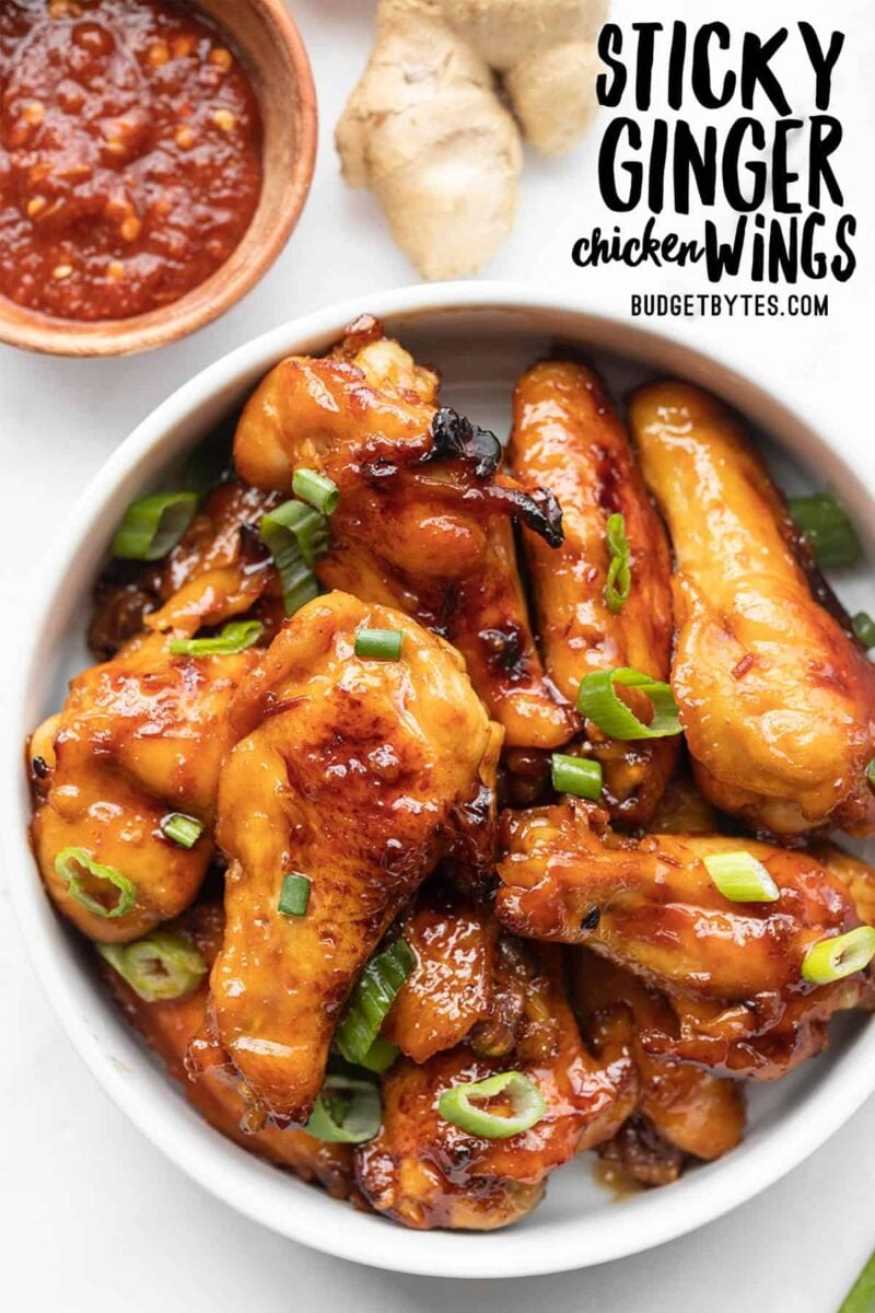 Overhead view of a bowl of sticky ginger chicken wings, title text at the top