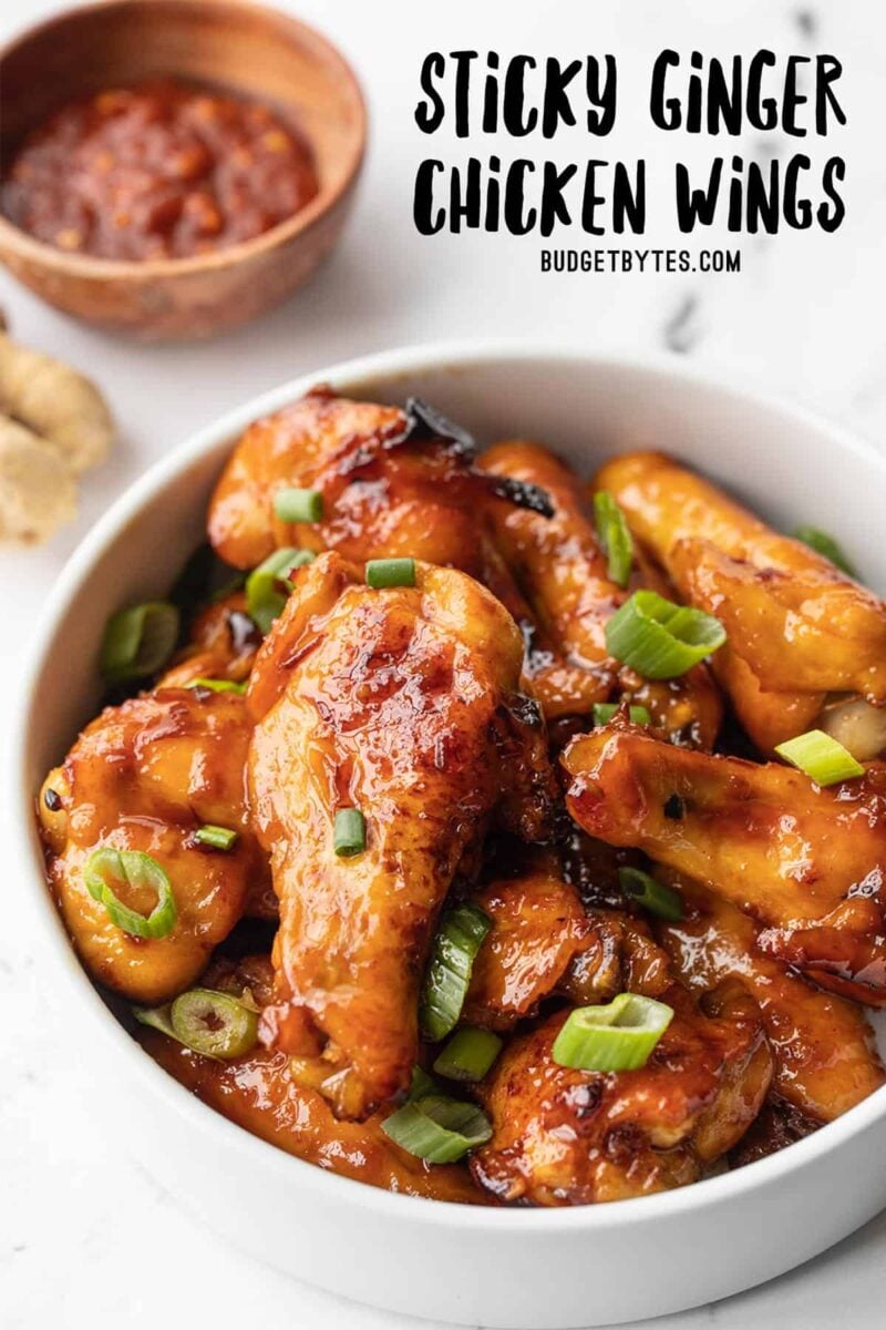 Side view of a bowl full of sticky ginger chicken wings, title text at the top