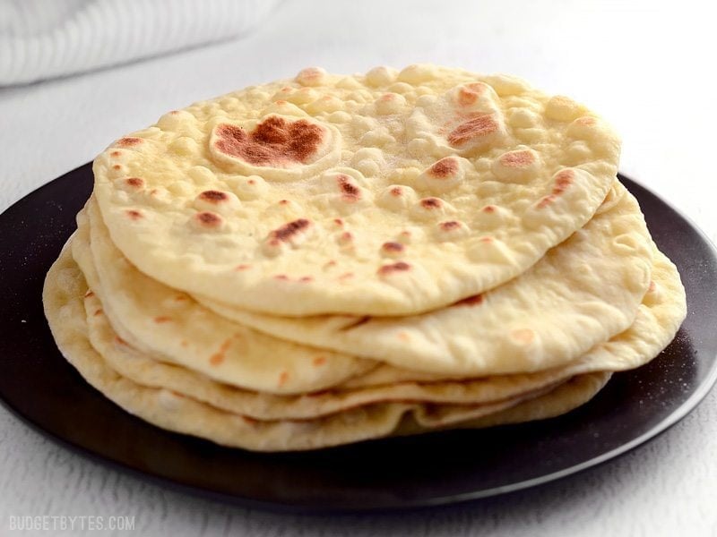 Front view of a stack of freshly baked naan on a plate. 