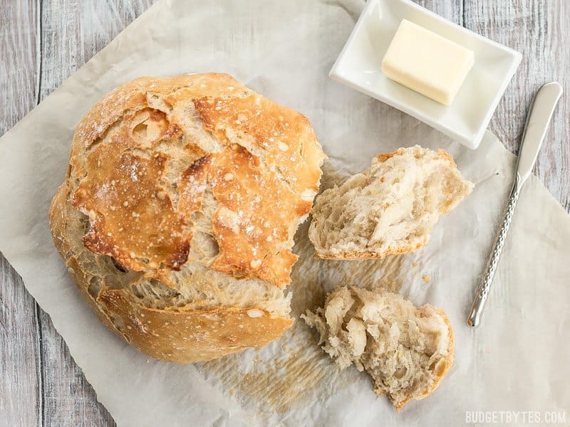 Overhead shot of a loaf of No-Knead Bread, with pieces torn, and butter on the side