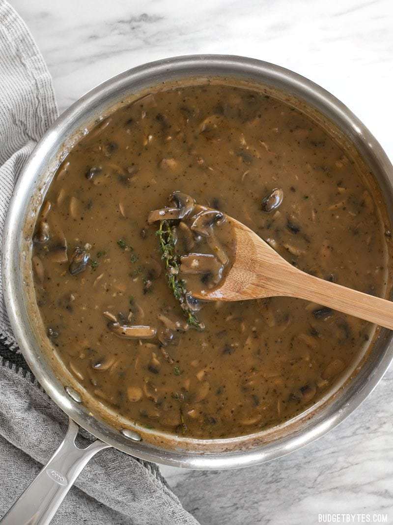 Top view of mushroom herb gravy in pan with wooden spoon