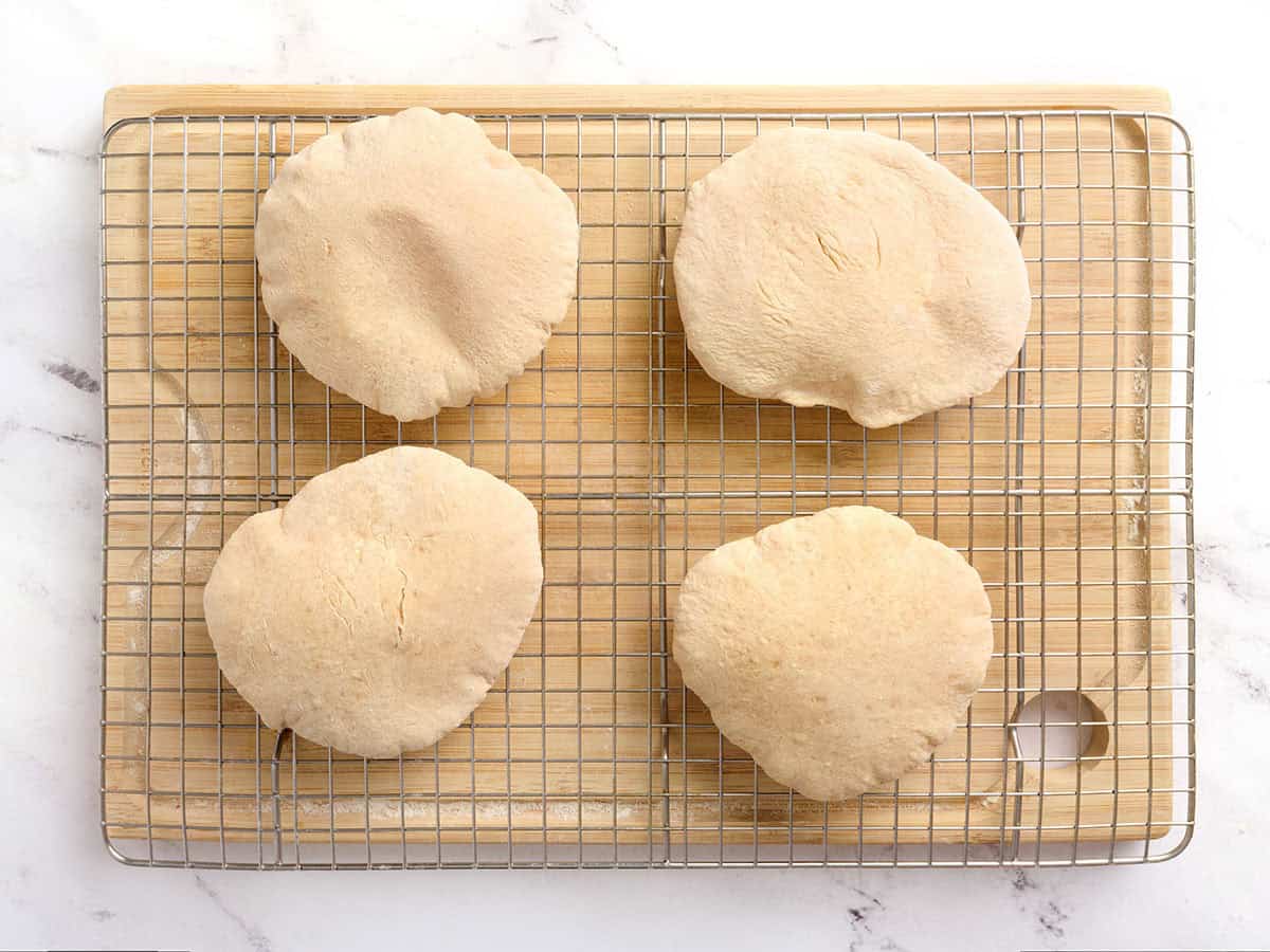 Homemade pita bread on a wire rack fresh out of the oven.