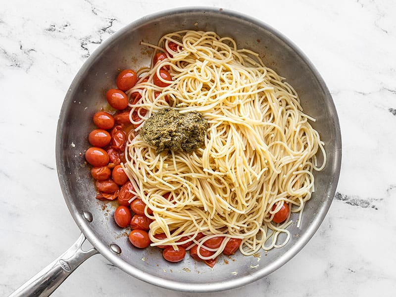 Cooked pasta and pesto added to the skillet with tomatoes and garlic