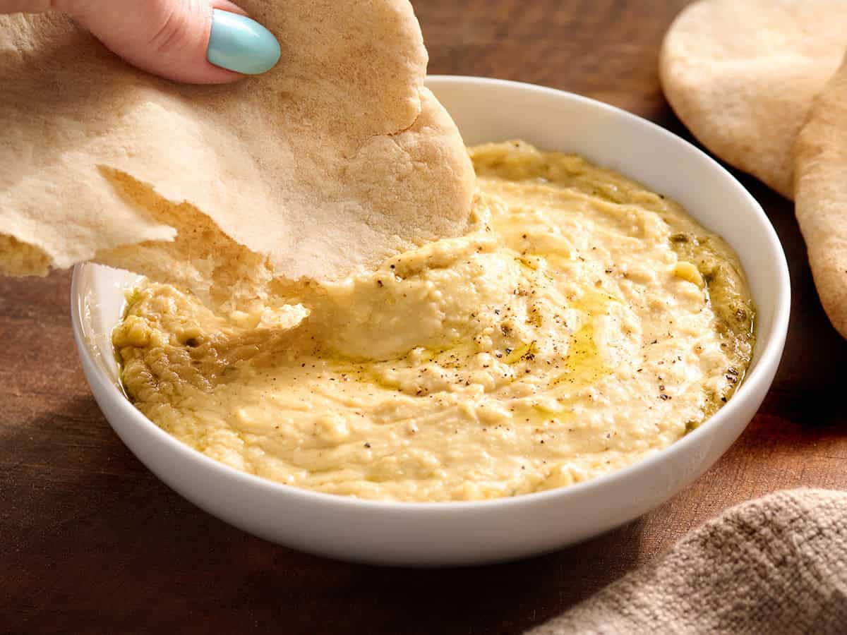 A homemade pita bread being dipped into hummus.