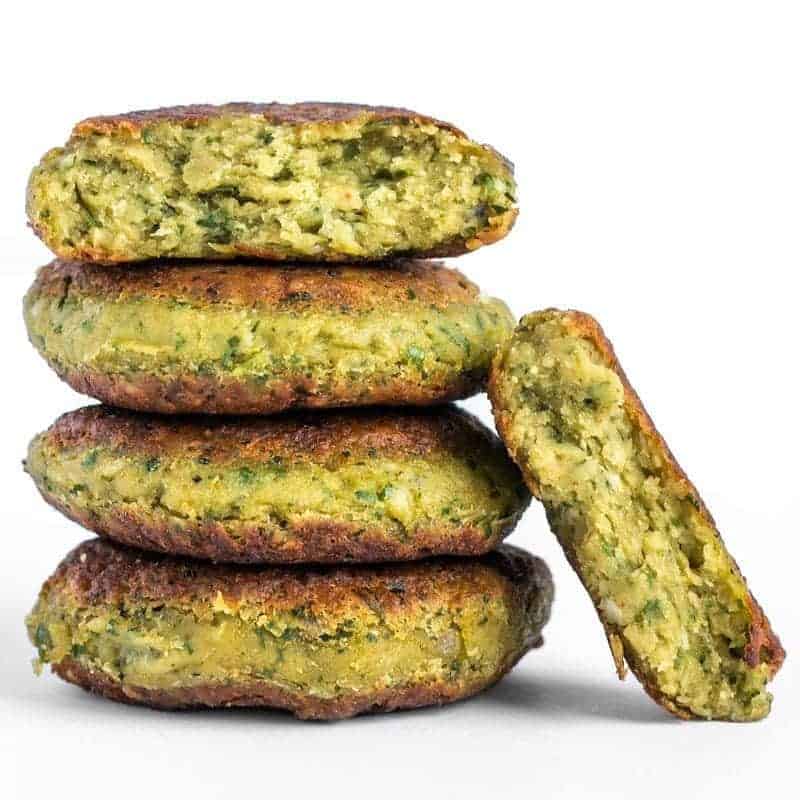 A stack of four cooked falafel with one broken in half and leaning on the side.