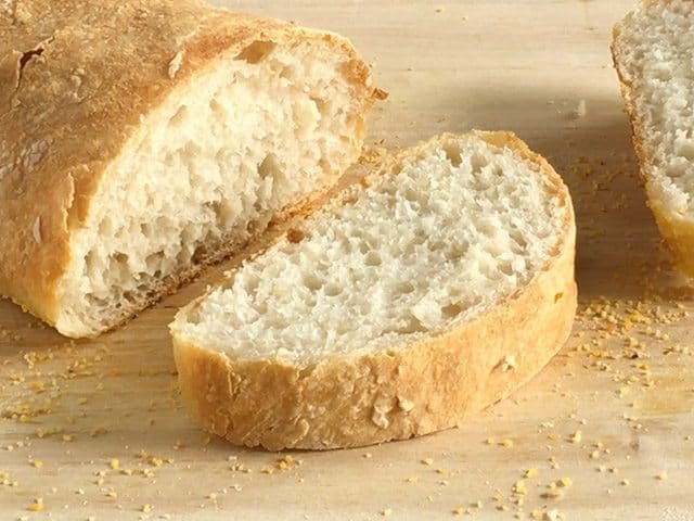 No-Knead Ciabatta on wooden cutting board with one slice sliced off 