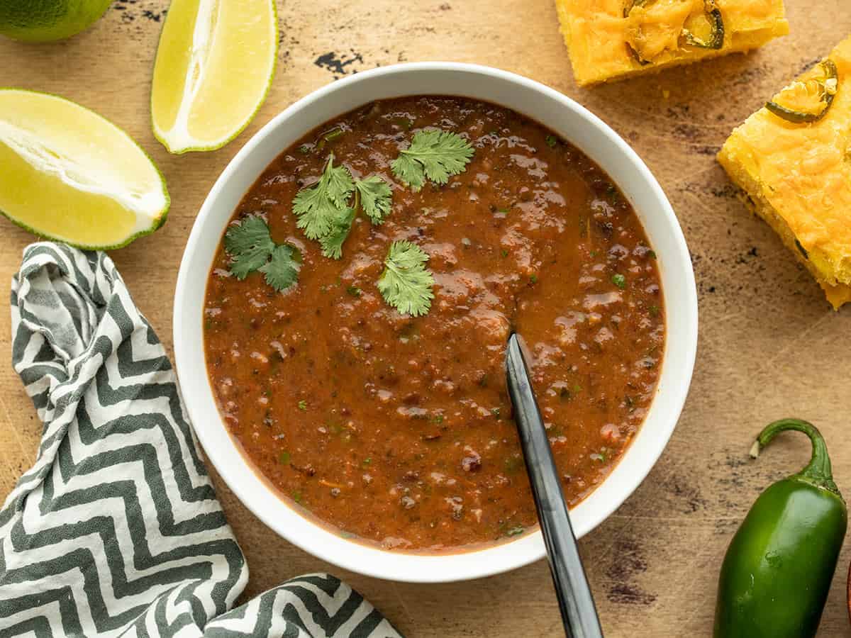 Overhead view of a bowl full of black bean and roasted salsa soup with a spoon in the center