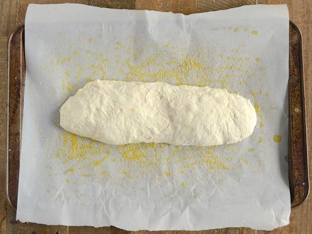 Baking sheet lined with parchment paper with shaped Ciabatta Dough placed on top ready to cook 