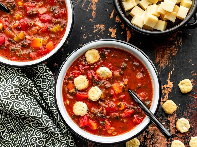 Two bowls of Swamp Soup with a bowl of Swiss cheese on the side, plus a few oyster crackers