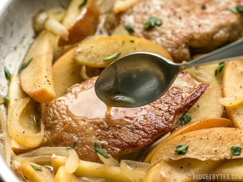 Pan sauce being drizzled over Apple Spice Pork Chops in the skillet