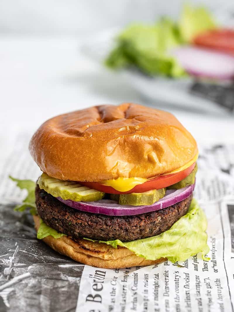 Side view of a black bean burger with toppings in the background