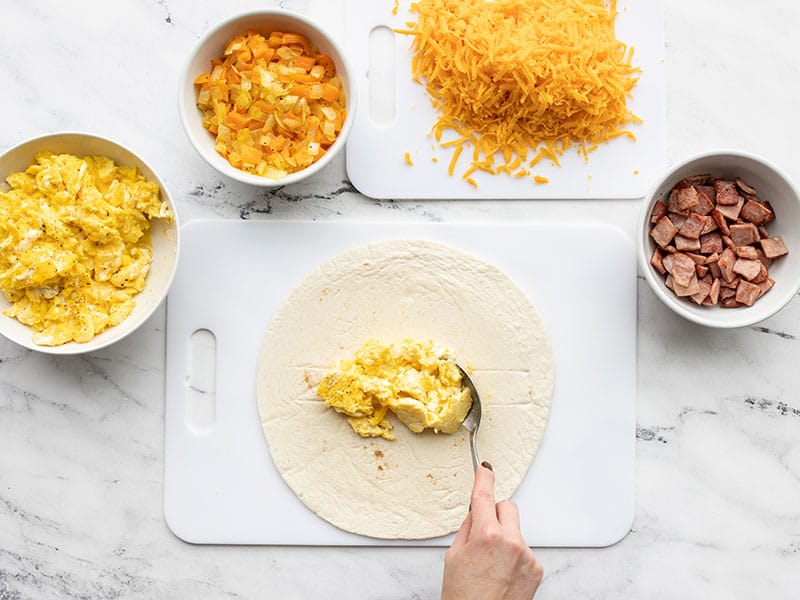 Build breakfast burritos, eggs on tortillas first