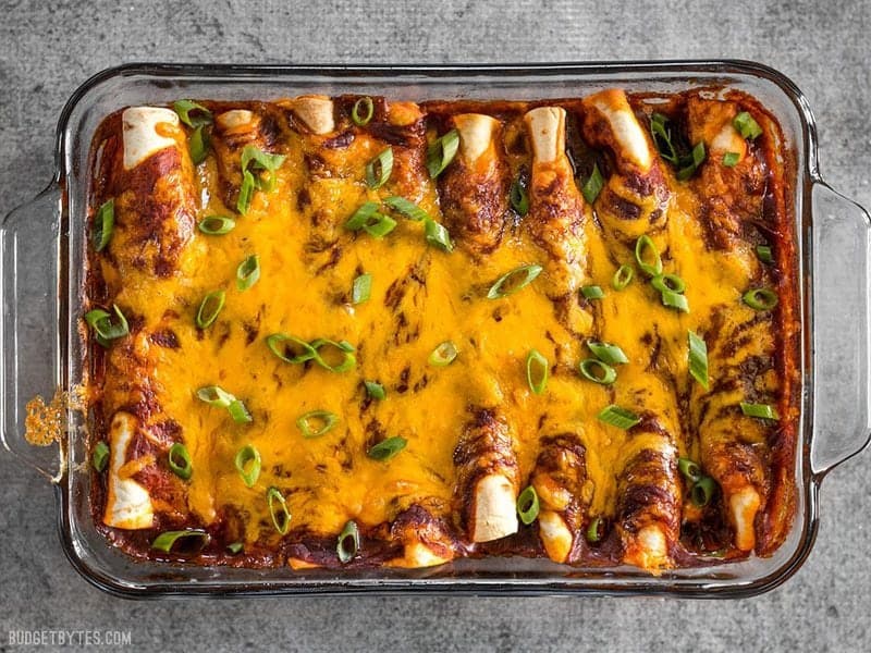 Baked Chorizo and Sweet Potato enchiladas in the casserole dish, garnished with green onion