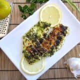 Above angle of garlic lemon fish served with lemon.