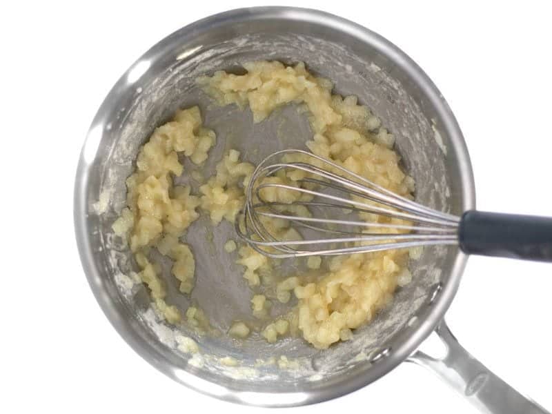 Flour added to onion and butter to create roux, mixed with whisk 