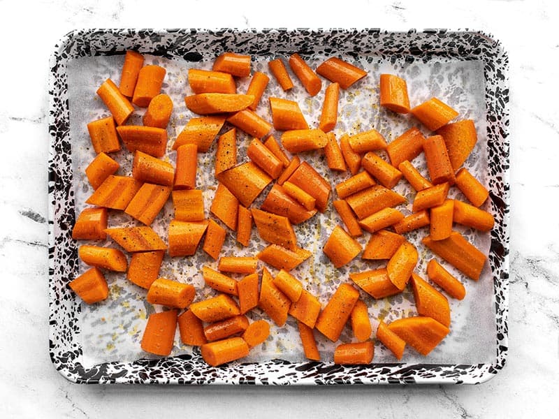 Seasoned carrots on a baking sheet ready to roast